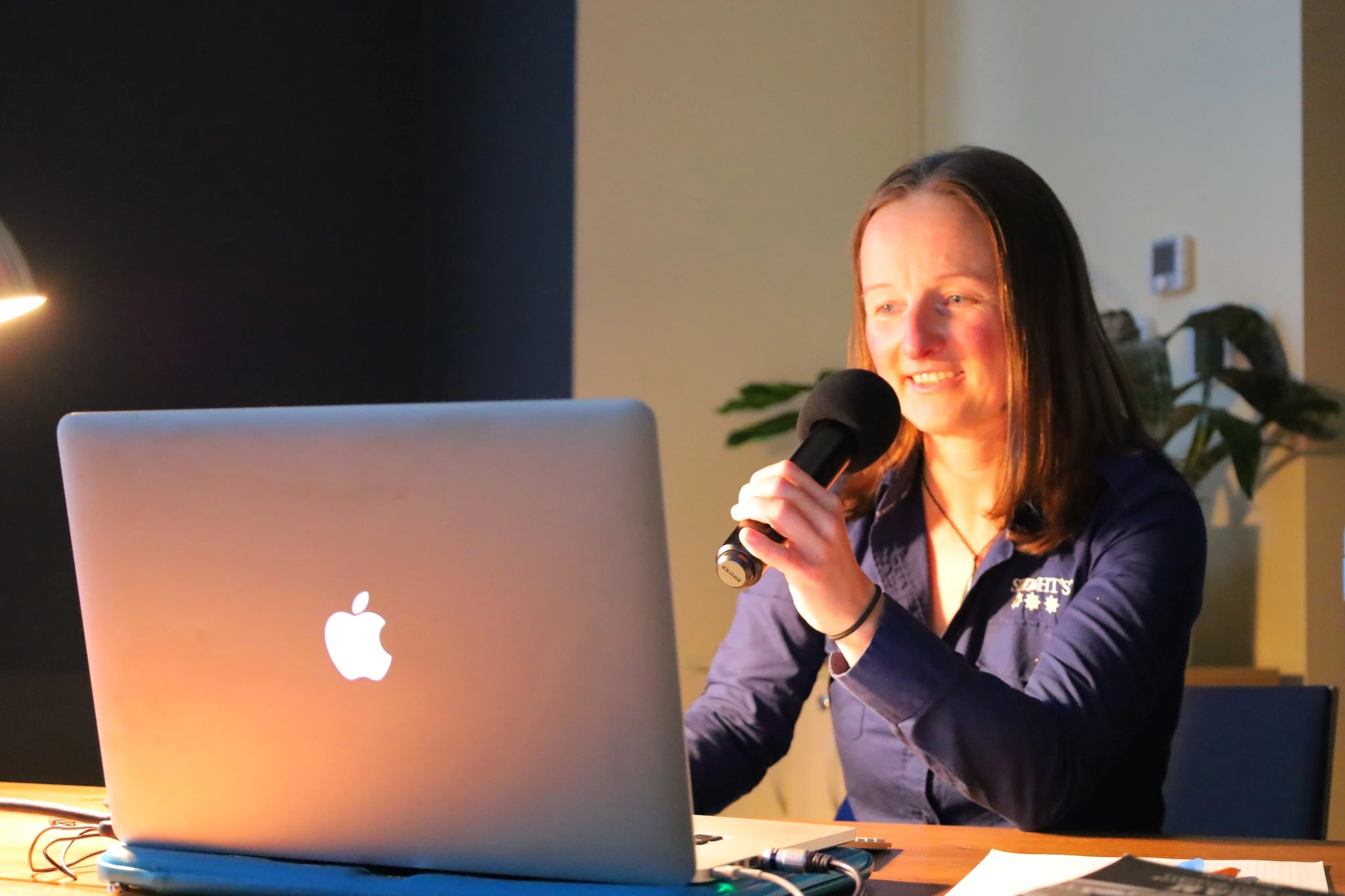 Joanna Tuszyńska speaking into a microphone at the New Zealand talk at ODK Zasole.