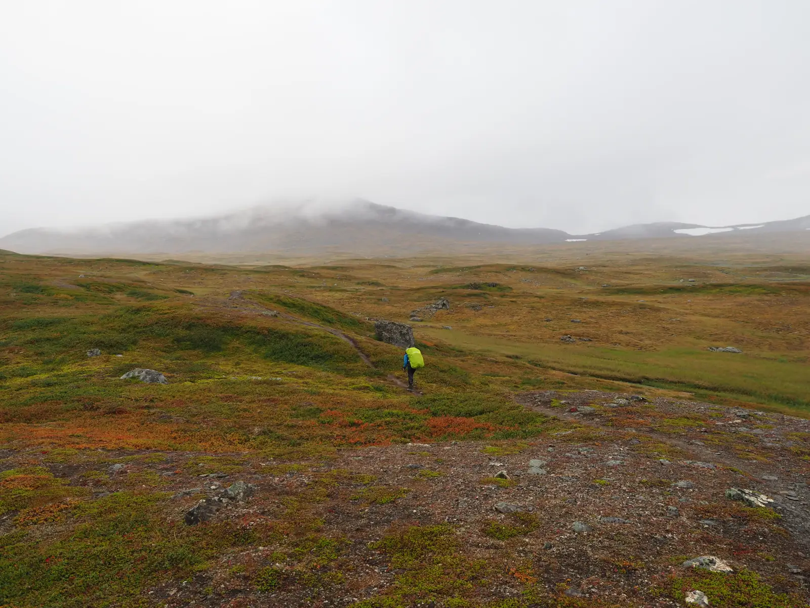 Rafał crossing open tundra beneath mist-covered mountains. Sarek NP, 2026