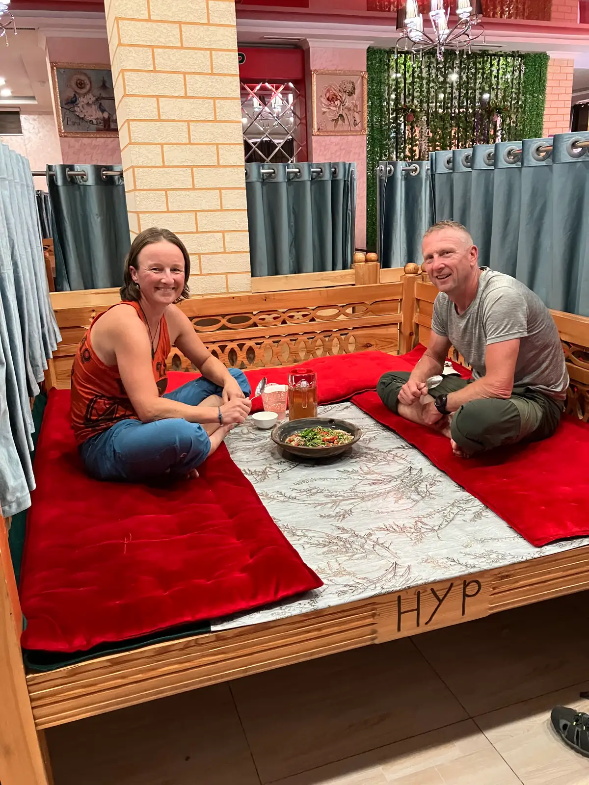 Joanna and Rafał sitting on a tapchan in a traditional restaurant in Dushanbe, with kurutob, a traditional Tajik dish.