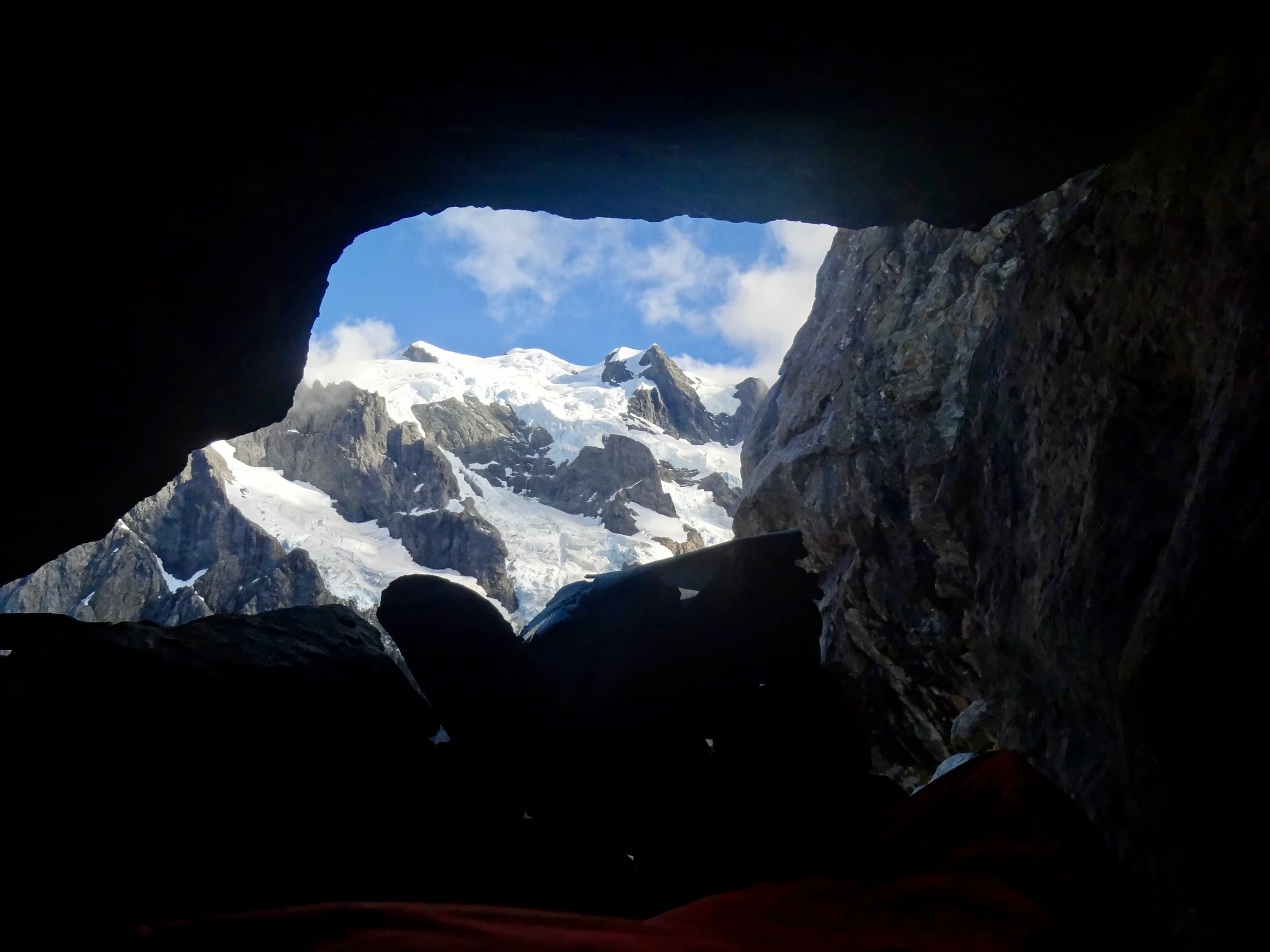 Mount Tutoko's snowy summit seen through a rock opening in Turner's Biv.