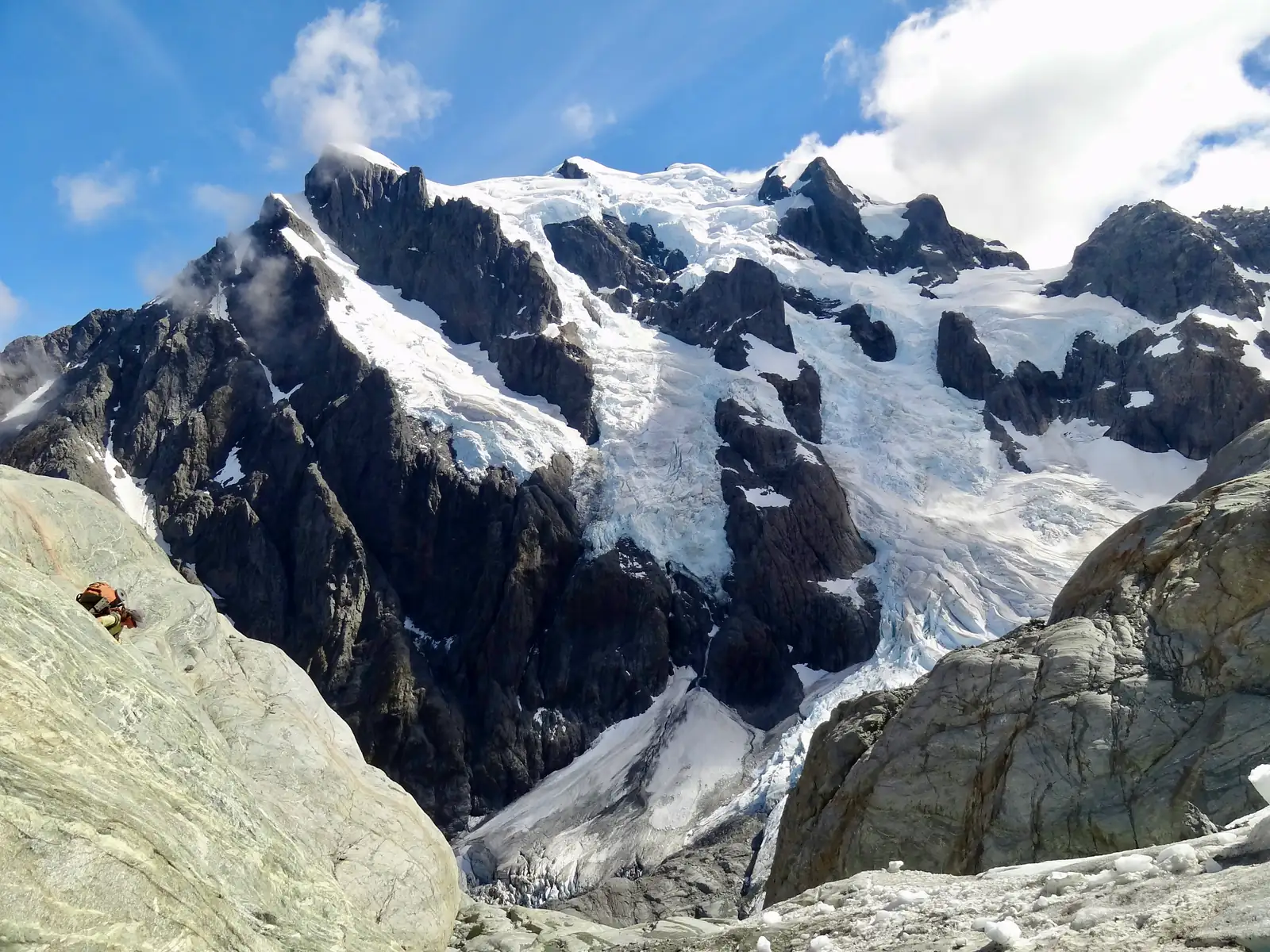 Walking on the rocky ledges from Turner's Biv towards the last campsite. Mount Tutoko's south face in the background