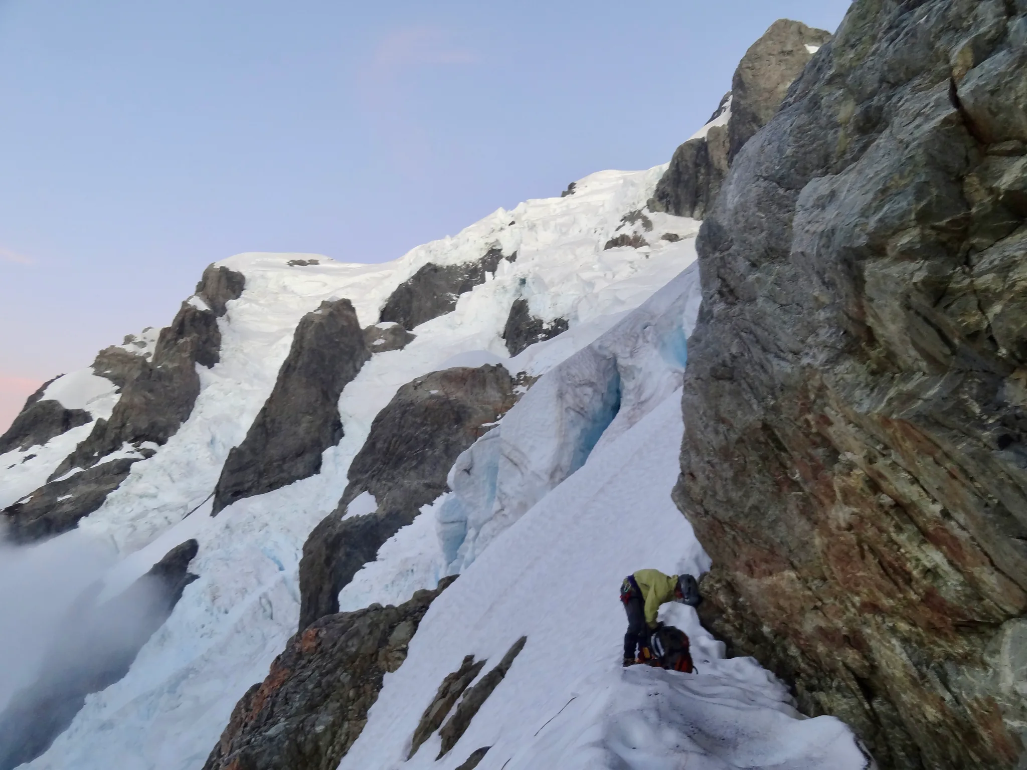 A small snow ledge beside a steep rock wall on Mount Tutoko.