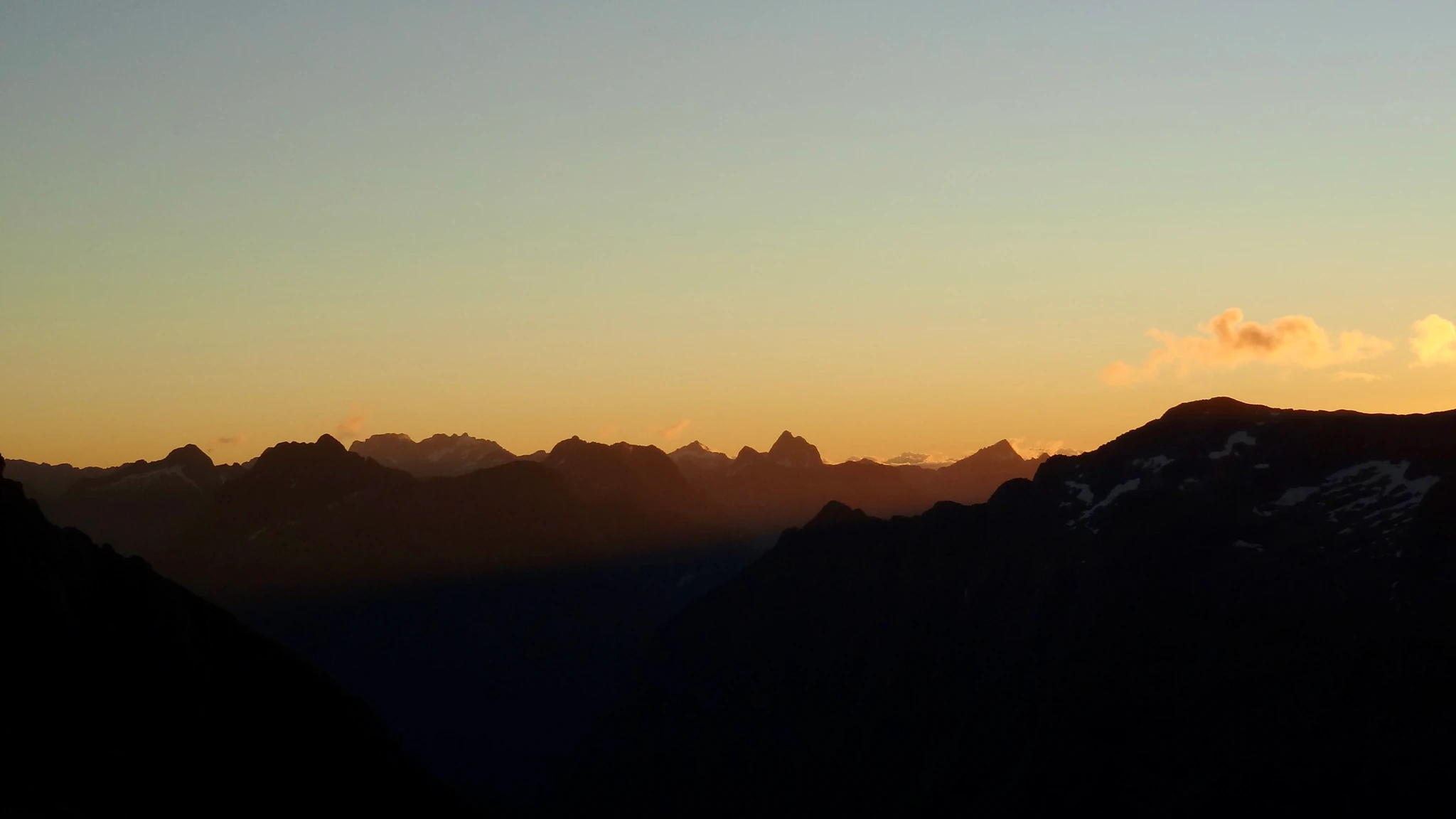 Mountain ridges silhouetted against a golden sunset sky.