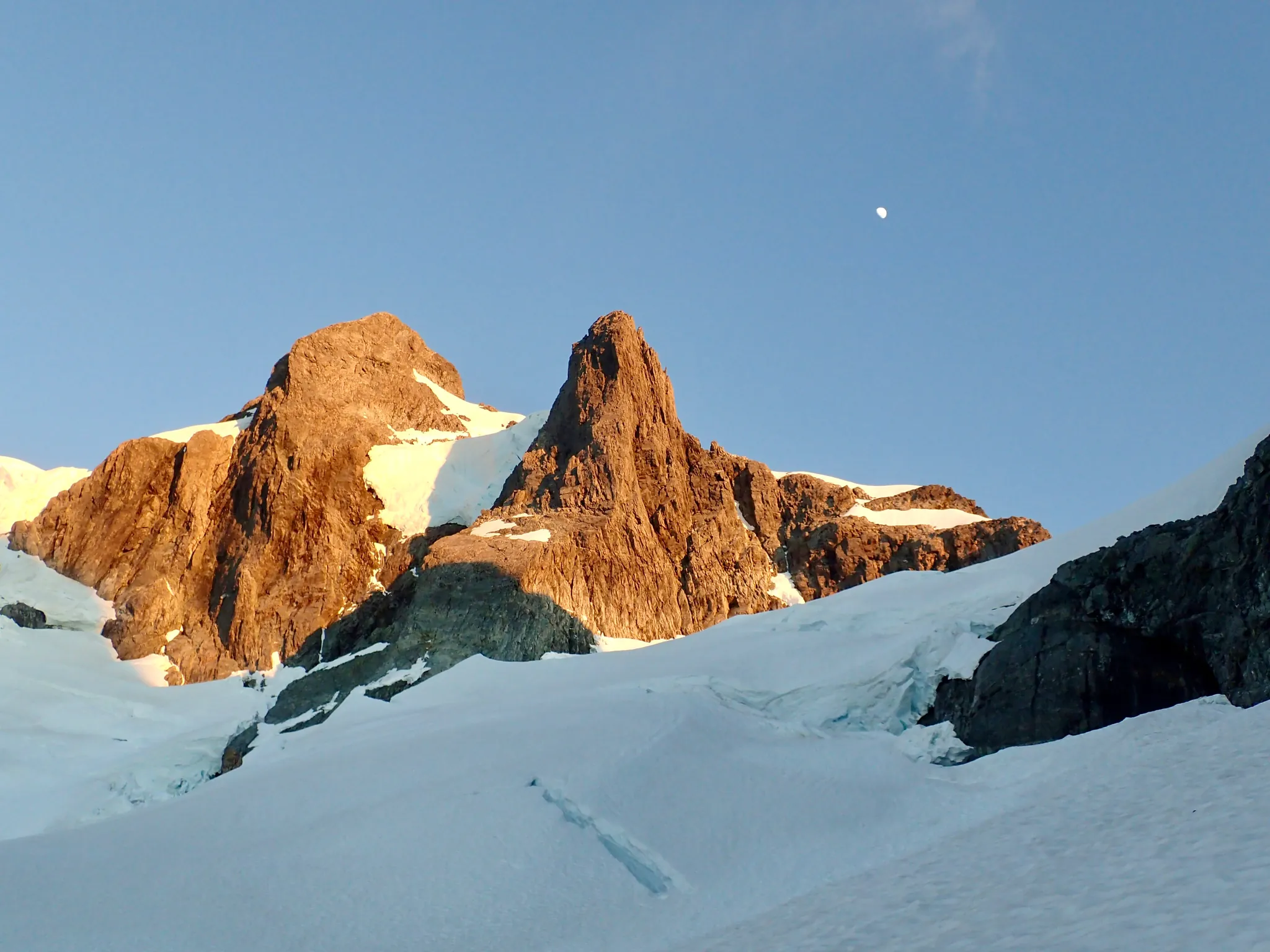 Middle section of the snowy slope on Mount Tutoko. Willie stands beside a large crevasse.
