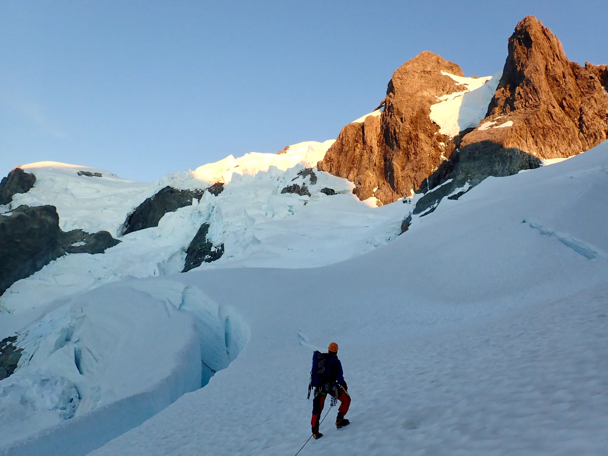 Middle section of the snowy slope on Mount Tutoko. Willie stands beside a large crevasse.