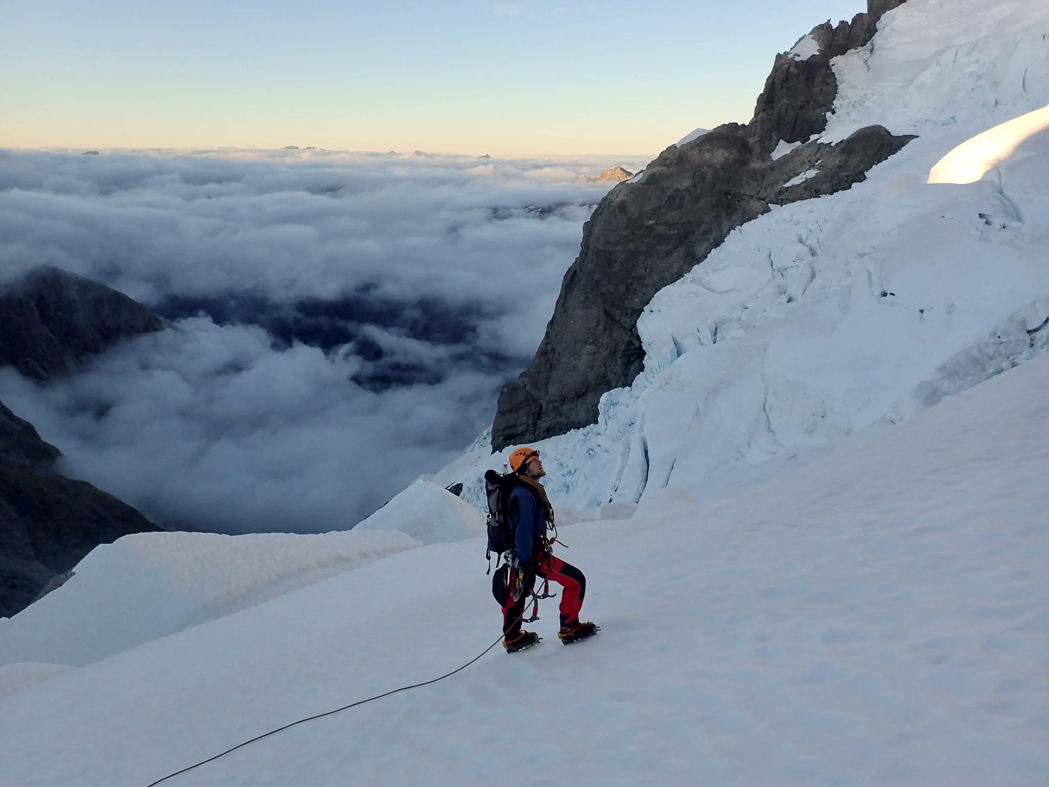 Willie on the middle slopes of Mount Tutoko, with a sea of clouds behind him.