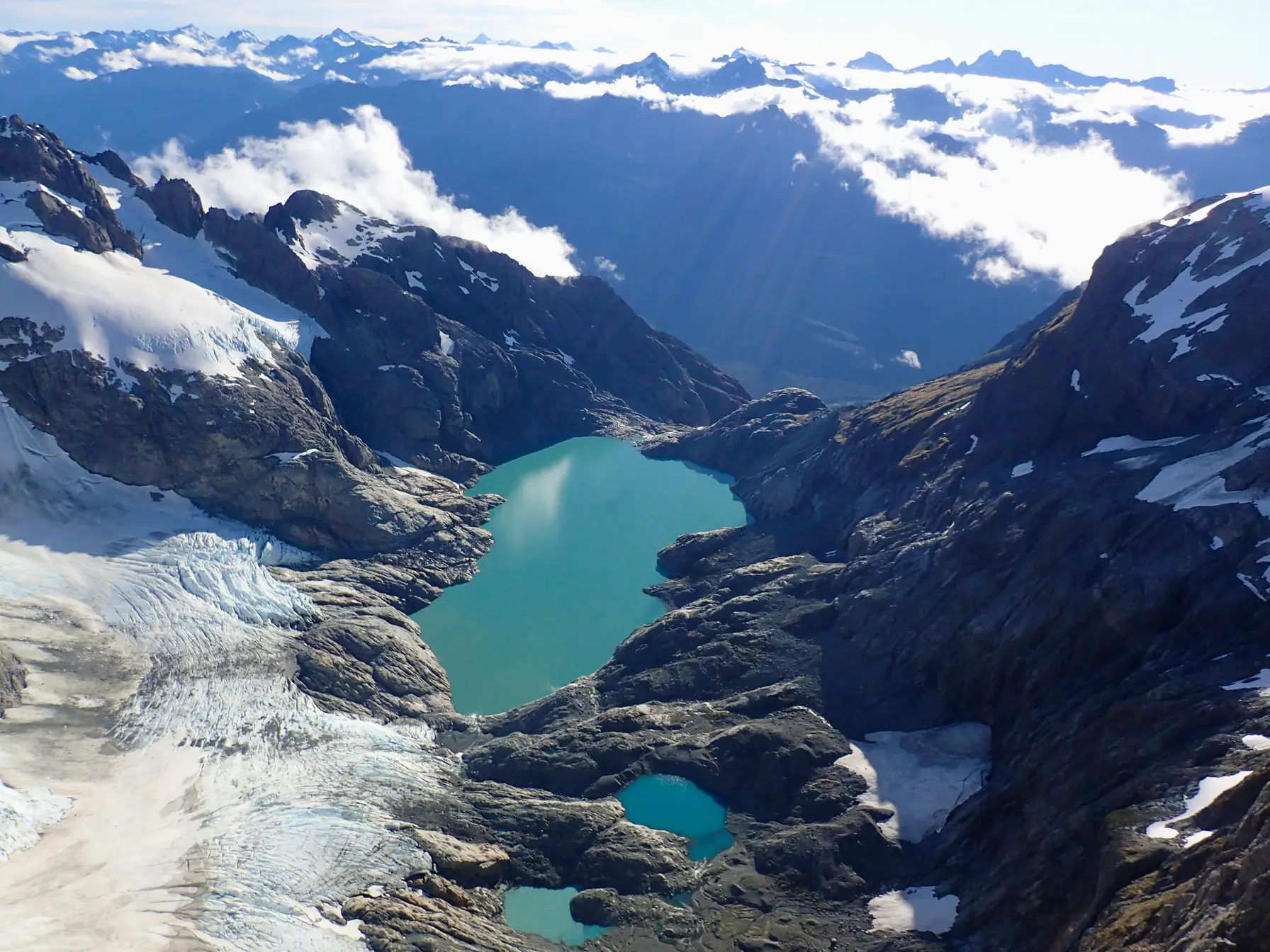Turquoise alpine lakes surrounded by rock, snow and ice.